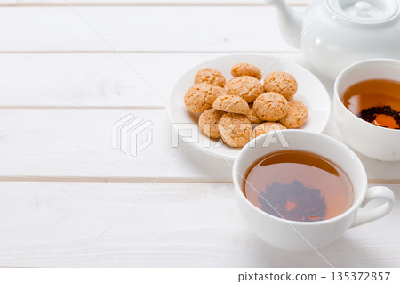 Warm tea and cookies on a white wooden table during afternoon snack time Warm tea and cookies on a white wooden table during afternoon snack time 135372857