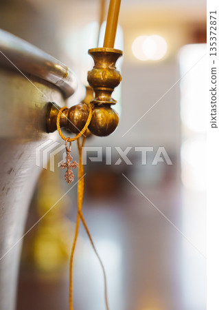 Cross hanging from a golden faucet in a quiet room 135372871