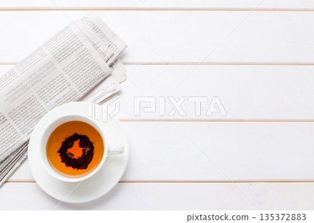 Coffee cup with newspaper on wooden table in morning light Coffee cup with newspaper on wooden table in morning light 135372883