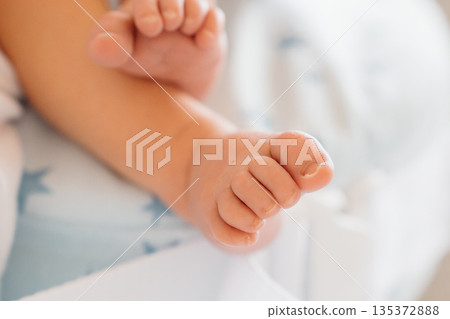 Baby feet resting on a soft blanket in a bright room 135372888