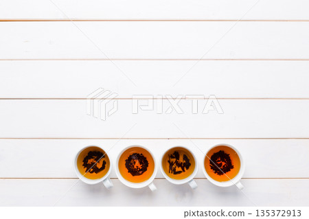Four cups of tea with unique patterns on a white wooden table 135372913