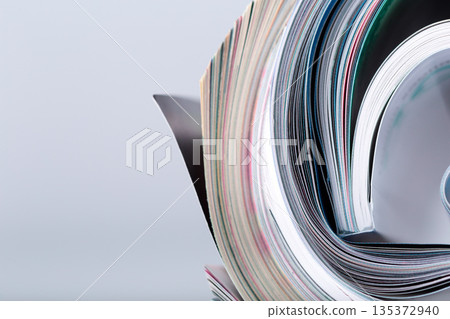 Magazines stacked and slightly open showing pages and colorful content in a casual display Magazines stacked and slightly open showing pages and colorful content in a casual display 135372940