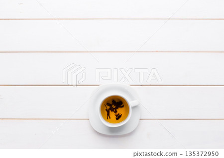 Coffee sits in a white cup on a wooden table during daytime Coffee sits in a white cup on a wooden table during daytime 135372950