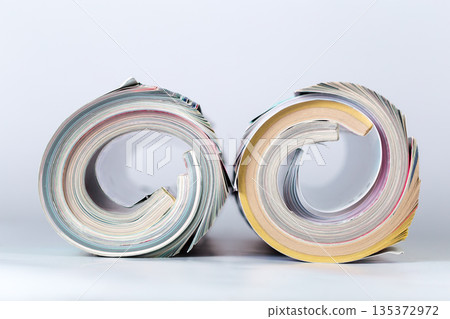 Piles of rolled magazines arranged side by side on a plain background at a studio 135372972