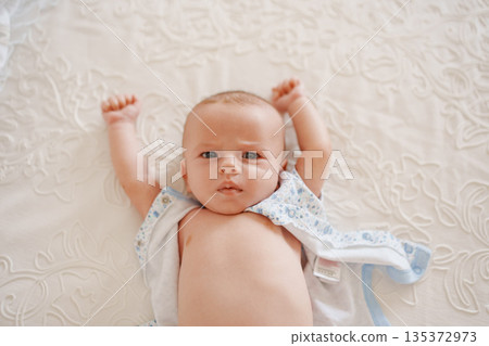Baby playing on white blanket with cheerful expression 135372973