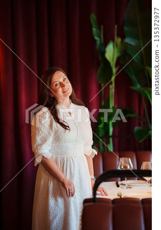 Elegant woman poses in restaurant with rich decor 135372977