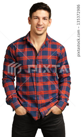 Smiling man wearing a plaid shirt stands with hands in pockets indoors Smiling man wearing a plaid shirt stands with hands in pockets indoors 135372986
