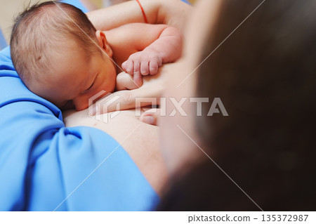 Newborn baby breastfeeding with mother in a cozy setting 135372987