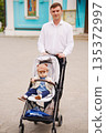 Father enjoys a day out with baby in stroller 135372997