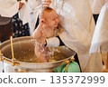 Baptism ceremony with a baby being baptized in water 135372999