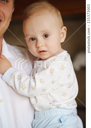 Father holding baby boy indoors during daytime 135373003