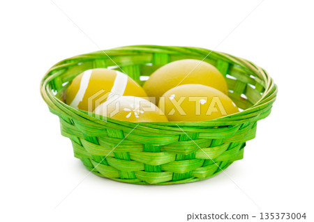 Colorful basket holds yellow eggs with simple designs for seasonal celebration 135373004