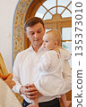 Man holding baby during special event in bright room 135373010