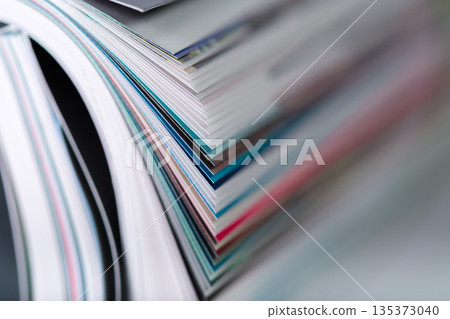 Stacked pages from various magazines showing different colors and textures on a table 135373040