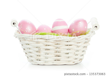 Colorful eggs in a white basket with green grass on a plain background 135373063