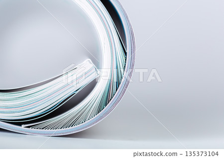 Curled stack of colorful papers on a plain surface showing different shades and textures 135373104