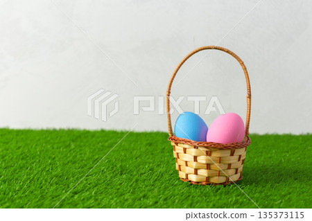 Basket with blue and pink eggs on green grass background during Easter season Basket with blue and pink eggs on green grass background during Easter season 135373115