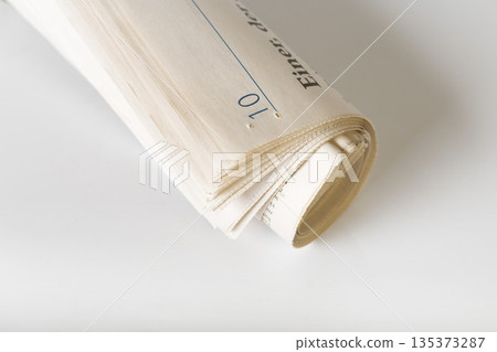 Curled stack of paper with visible writing and markings on a plain surface Curled stack of paper with visible writing and markings on a plain surface 135373287
