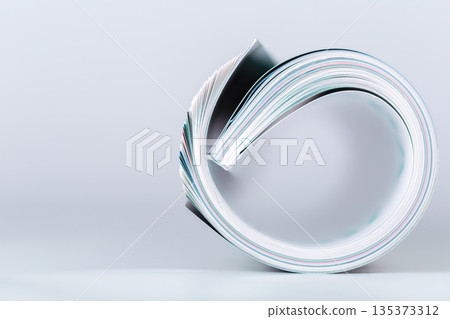 Curled stack of paper lies on surface in simple arrangement 135373312