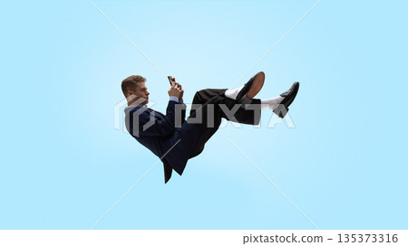 Business man levitating while reading smartphone notifications. Business man levitating while reading smartphone notifications. 135373316