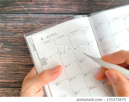 A woman filling out her April schedule book A woman filling out her April schedule book 135373675