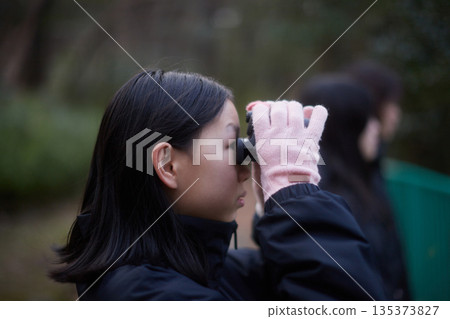冬日清晨，一位國中女生在森林裡用望遠鏡觀察野生鳥類。 135373827