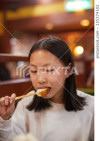 A cute junior high school girl eating mochi at a cafe in winter 135374102