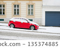 Red Car Covered in Snow on Urban Street 135374885