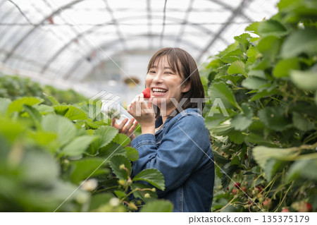 A woman holding a strawberry with a smile 135375179