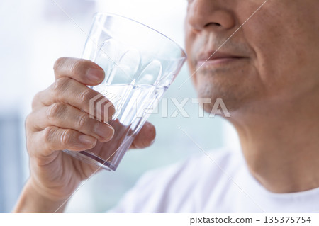 Senior men drinking water at the windowside Senior men drinking water at the windowside 135375754