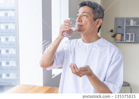 一位老人在窗邊吃藥 一位老人在窗邊吃藥 135375815
