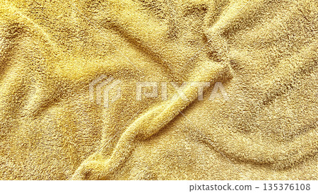 golden terry cloth texture folds in soft luxurious waves closeup for spa wellness wallpaper or commercial bath background 135376108