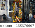 Mirror with an original design stands near the salon. Vertical mirror, festively decorated with a decorative garland of autumn leaves, adorns the entrance to the hairdressing salon 135376607