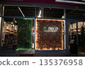Illuminated storefront with unique vertical garden displays. Festively decorated New Year's shop windows. 135376958