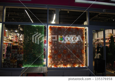 Illuminated storefront with unique vertical garden displays. Festively decorated New Year's shop windows. Illuminated storefront with unique vertical garden displays. Festively decorated New Year's shop windows. 135376958