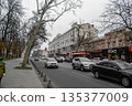 Urban street scene with cars and bare trees on an overcast day. Urban street scene in Odessa, Ukraine, featuring a busy road lined with cars and bare trees. 135377009