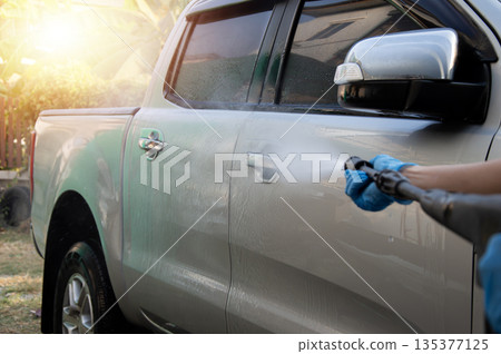 Washing a car with a high-pressure washer. Washing a car with a high-pressure washer. 135377125