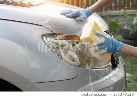 Washing a car with foam car wash solution. 135377129