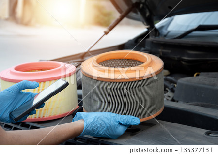 The mechanic is inspecting the old engine air filter. 135377131
