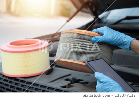 The mechanic is inspecting the old engine air filter. 135377132