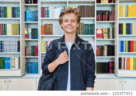 Portrait of smiling teenage student with backpack in classroom library Portrait of smiling teenage student with backpack in classroom library 135377351