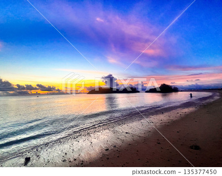 沖繩的日落和寧靜的海灘:絢麗的天空和輕柔的海浪。 沖繩的日落和寧靜的海灘:絢麗的天空和輕柔的海浪。 135377450