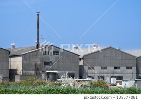 Chimneys towering against the blue sky and small factories with slate roofs create a nostalgic Japanese industrial landscape 135377861