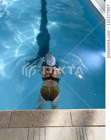 Swimmer Practices Strokes in Clear Water Under Bright Sunlight Swimmer Practices Strokes in Clear Water Under Bright Sunlight 135377907
