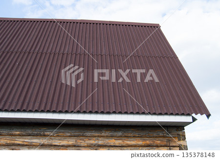 modern construction of the roof with red metal siding to a wooden house in the garden modern construction of the roof with red metal siding to a wooden house in the garden 135378148