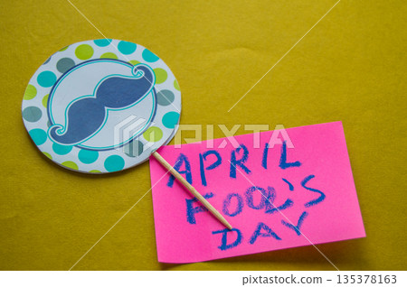 Paper topper with a painted mustache and the words April fool's day, yellow background Paper topper with a painted mustache and the words April fool's day, yellow background 135378163