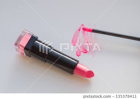 beautiful pink lip gloss smear with brush and a tube of lipstick, white background beautiful pink lip gloss smear with brush and a tube of lipstick, white background 135378411