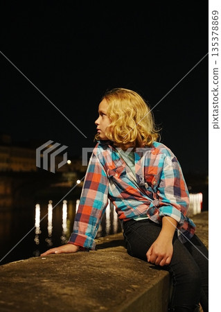 Child Sitting by River at Night in Contemplation Child Sitting by River at Night in Contemplation 135378869