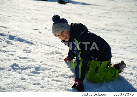Smiling Child Playing in the Snow During Winter Smiling Child Playing in the Snow During Winter 135378870