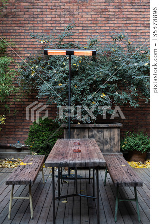 Cozy open-air terrace at street cafe with table, benches and infrared heater for comfortable rest. Cozy open-air terrace at street cafe with table, benches and infrared heater for comfortable rest. 135378896